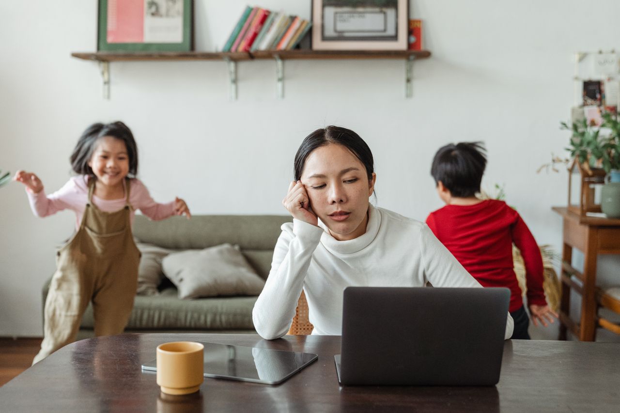 Mother balancing work at home while her children play nearby